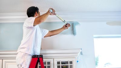 Profissional a pintar uma parede de interiores com rolo azul - dicas essenciais de pintura - Casa em Dia Maia