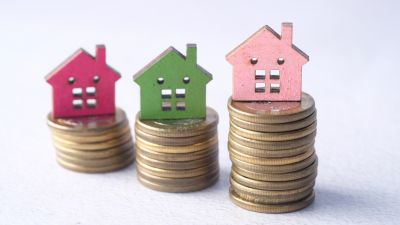 Casas em miniatura sobre pilhas de moedas - valorização de imóvel com pequenas obras - Casa em Dia Maia